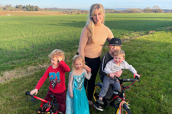 Lexi stands in a sunny field with her four young children