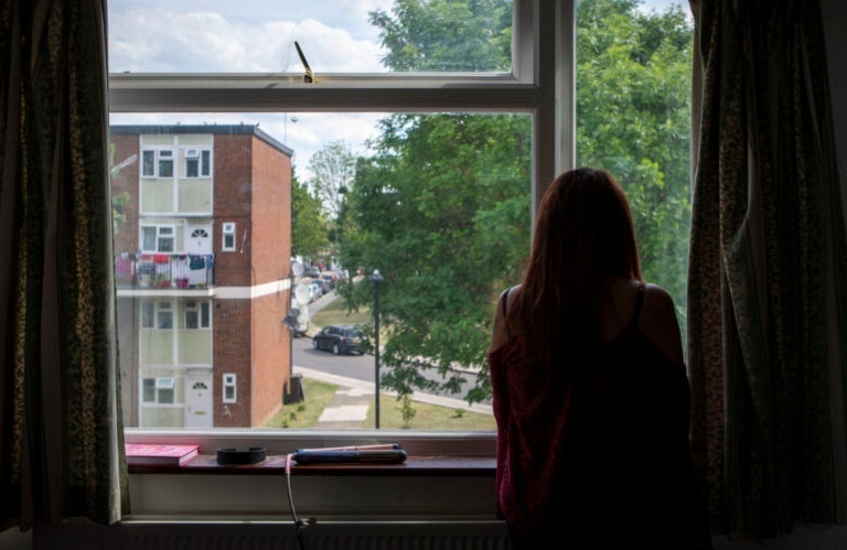 A woman looks out of a window from a block of flats