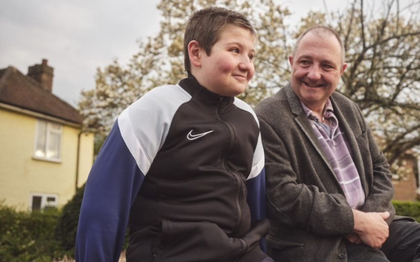 A father and son sitting outside a building.