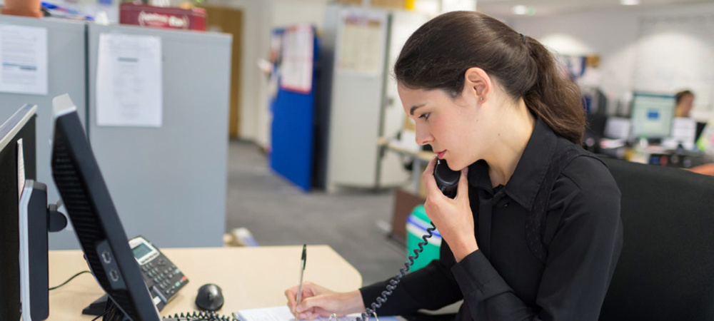 A member of Shelter staff takes down notes while she speaks to someone on the phone or helpline in the office