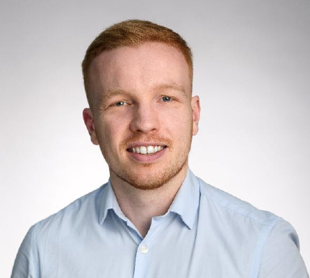 Corporate volunteer Freddie smiles in a professional headshot photograph wearing a blue shirt. He looks directly at the camera.
