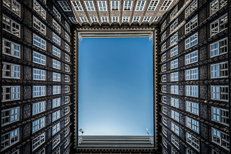 A low-to-ground view of apartments surrounding a courtyard, with blue sky above.