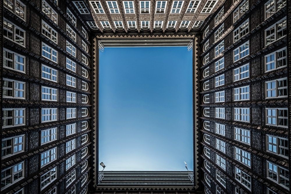 A low-to-ground view of apartments surrounding a courtyard, with blue sky above.