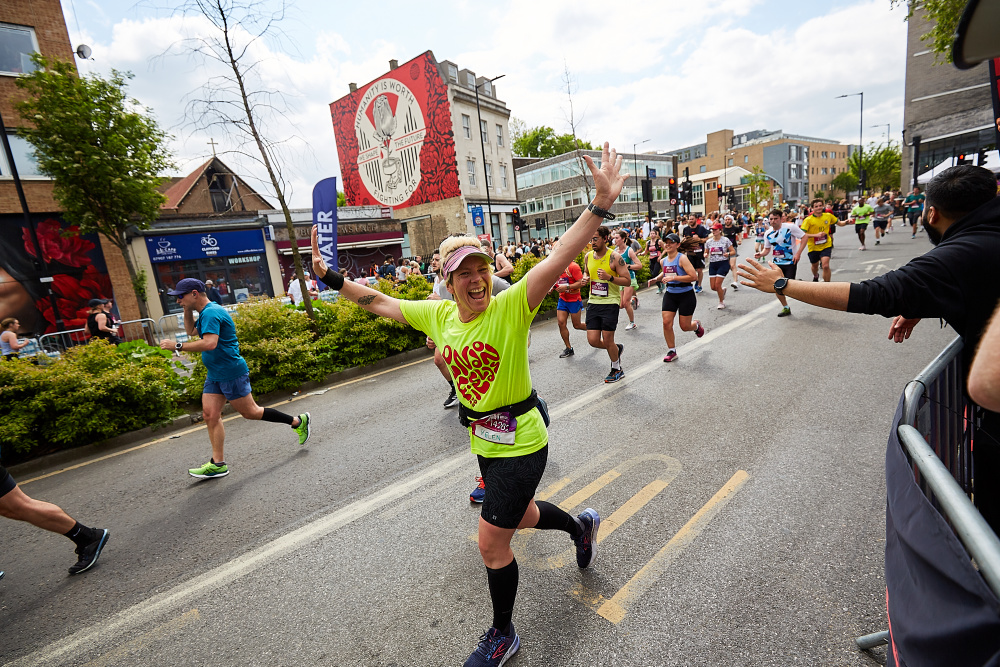 A happy marathon runner smiles with both arms outstretched 