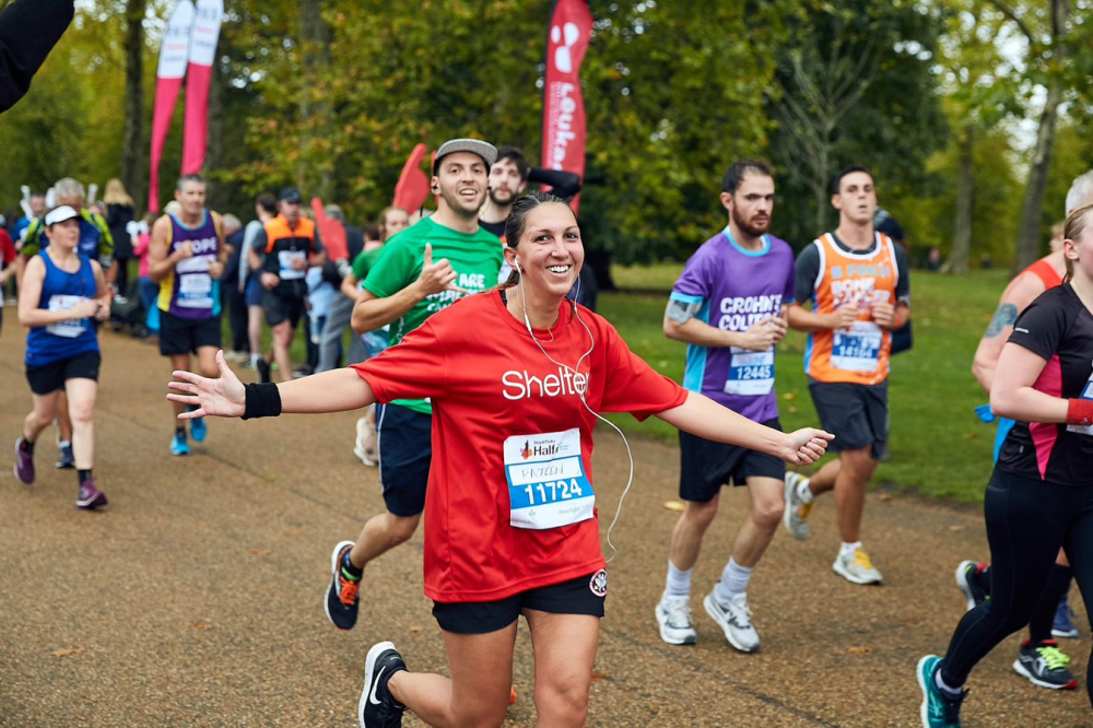 Woman in the middle of a running event, wearing a Shelter t-shirt and smiling at the camera. 