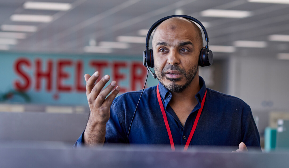 A member of Shelter helpline staff is wearing a headset and speaking on a call