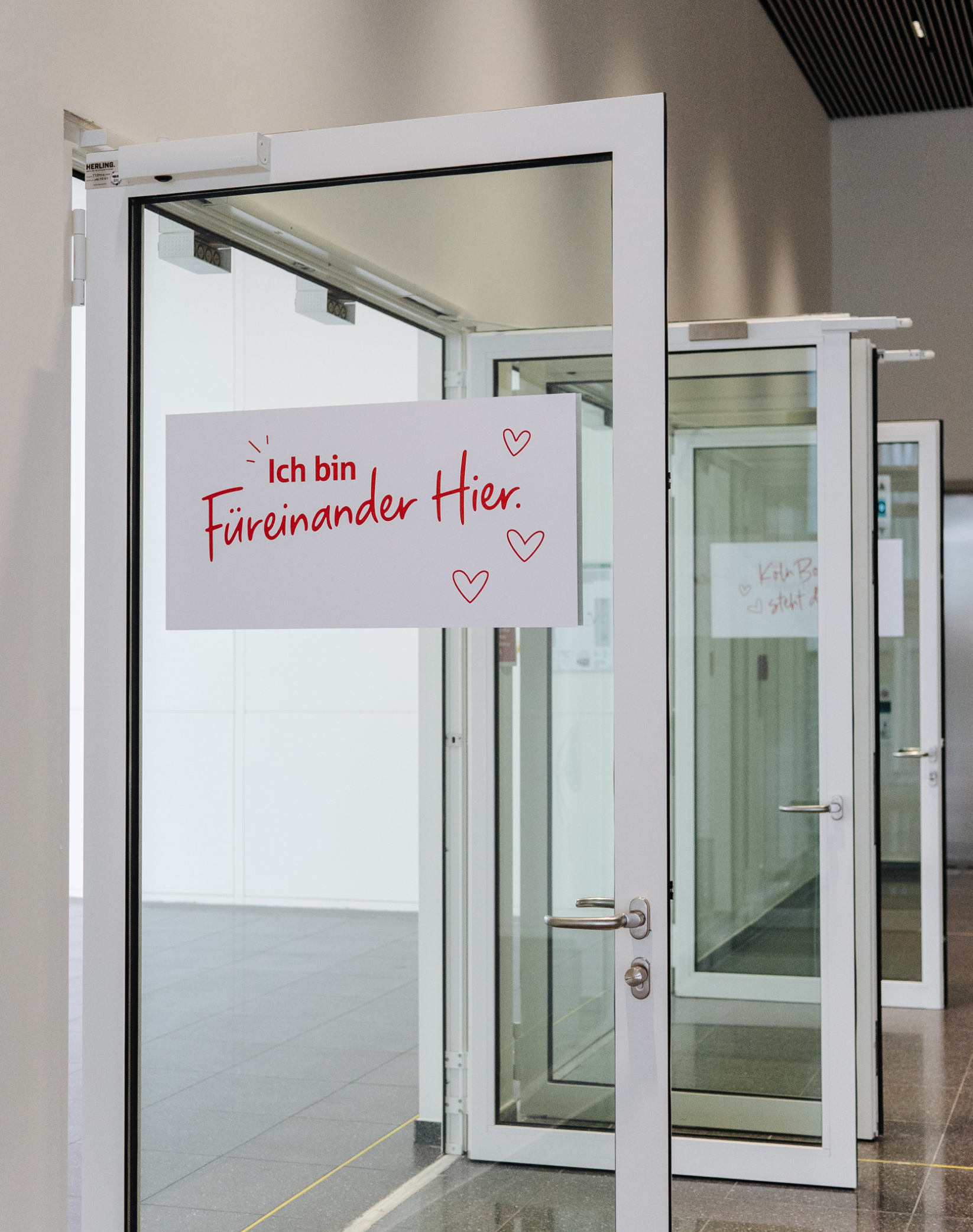 Glastür mit Aufschrift neuer Claim "Füreinander Hier."