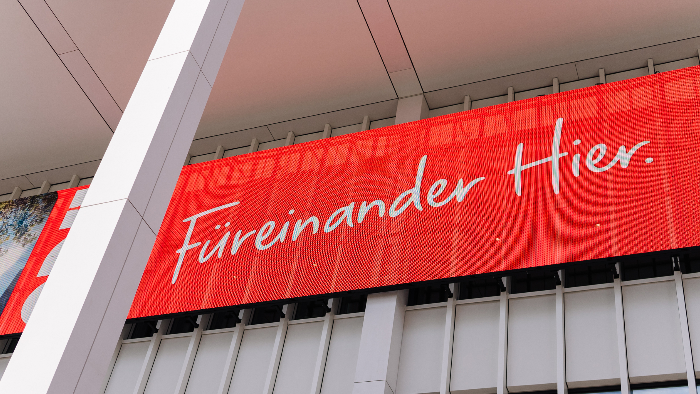 Illuminated display with claim "Füreinander Hier."
