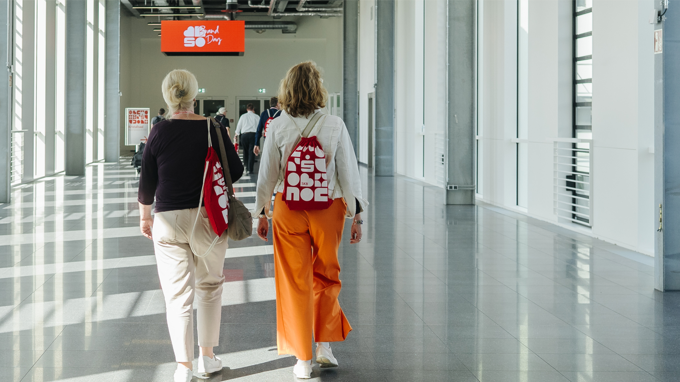 Zwei Personen von hinten mit rotem Rucksack im neuen Brand Design der Sparkasse KölnBonn