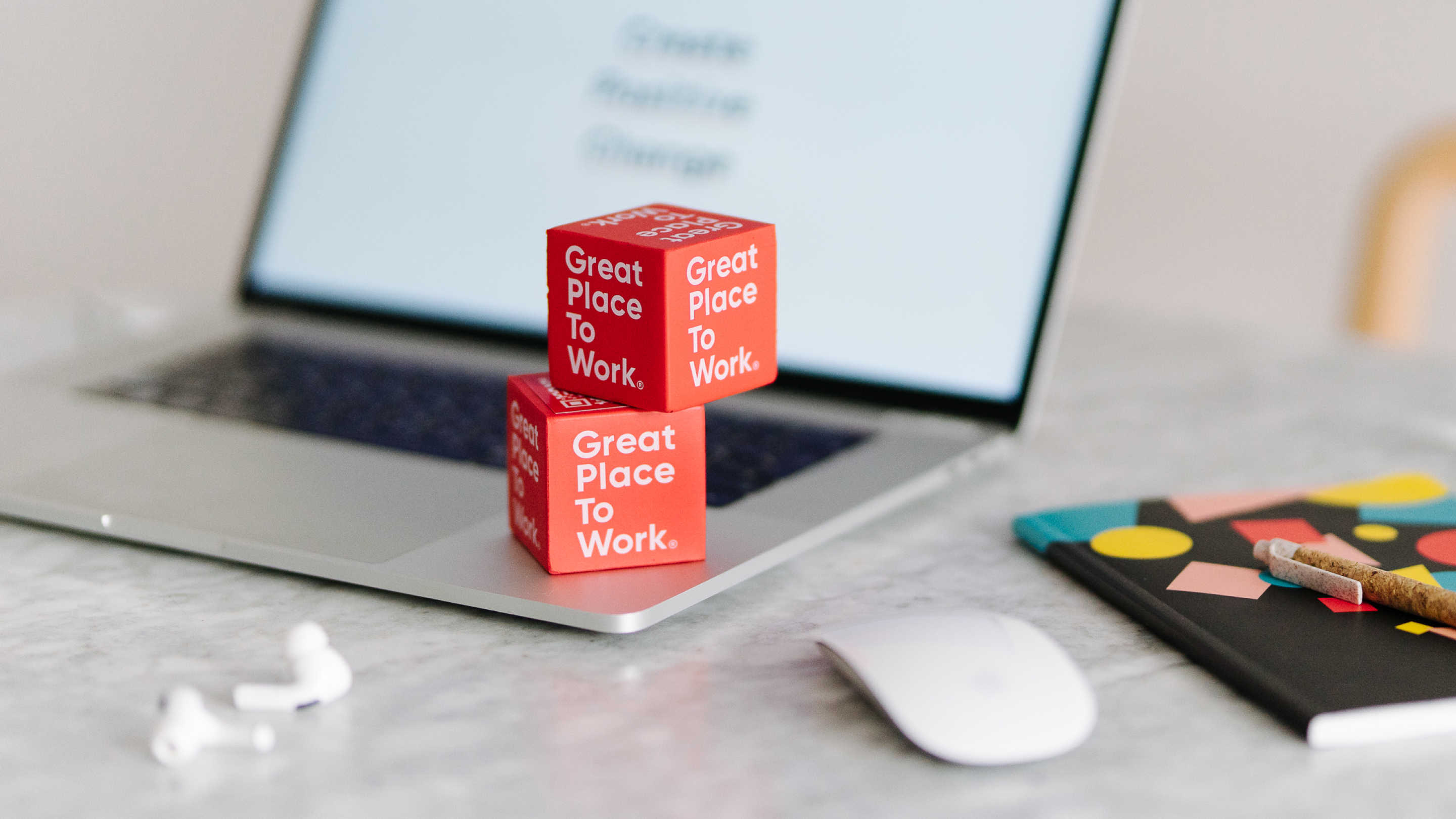 Picture of a laptop with two Great Place to Work cubes and denkwerk office supplies