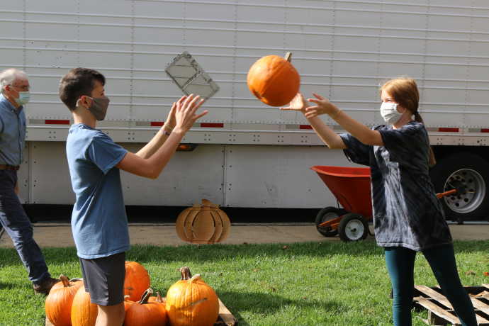 Two youth throwing a pumpkin