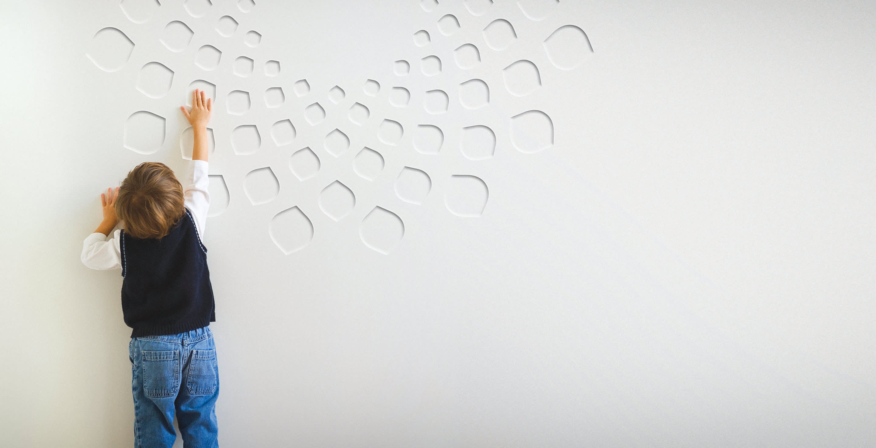A wide image of a boy reaching towards a concrete wall with the Bio Istanbul logo in relief on it.