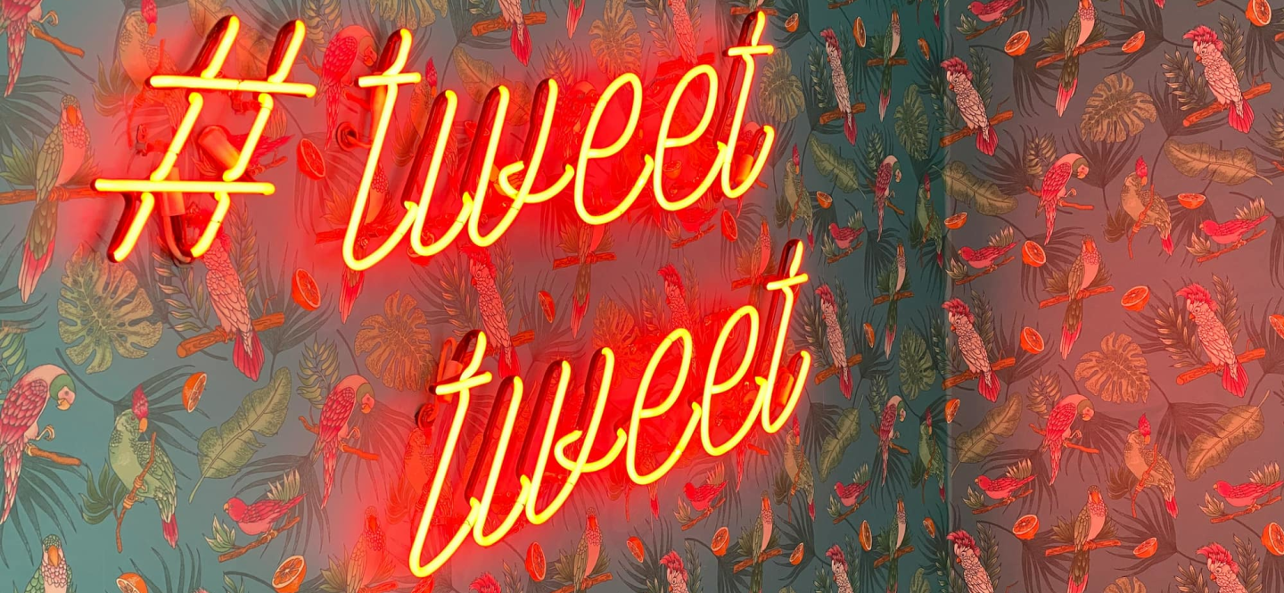 Neon sign saying Tweet Tweet on a patterned wall Photo by Chris J. Davis on Unsplash