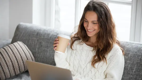Woman smiling with coffee and laptop