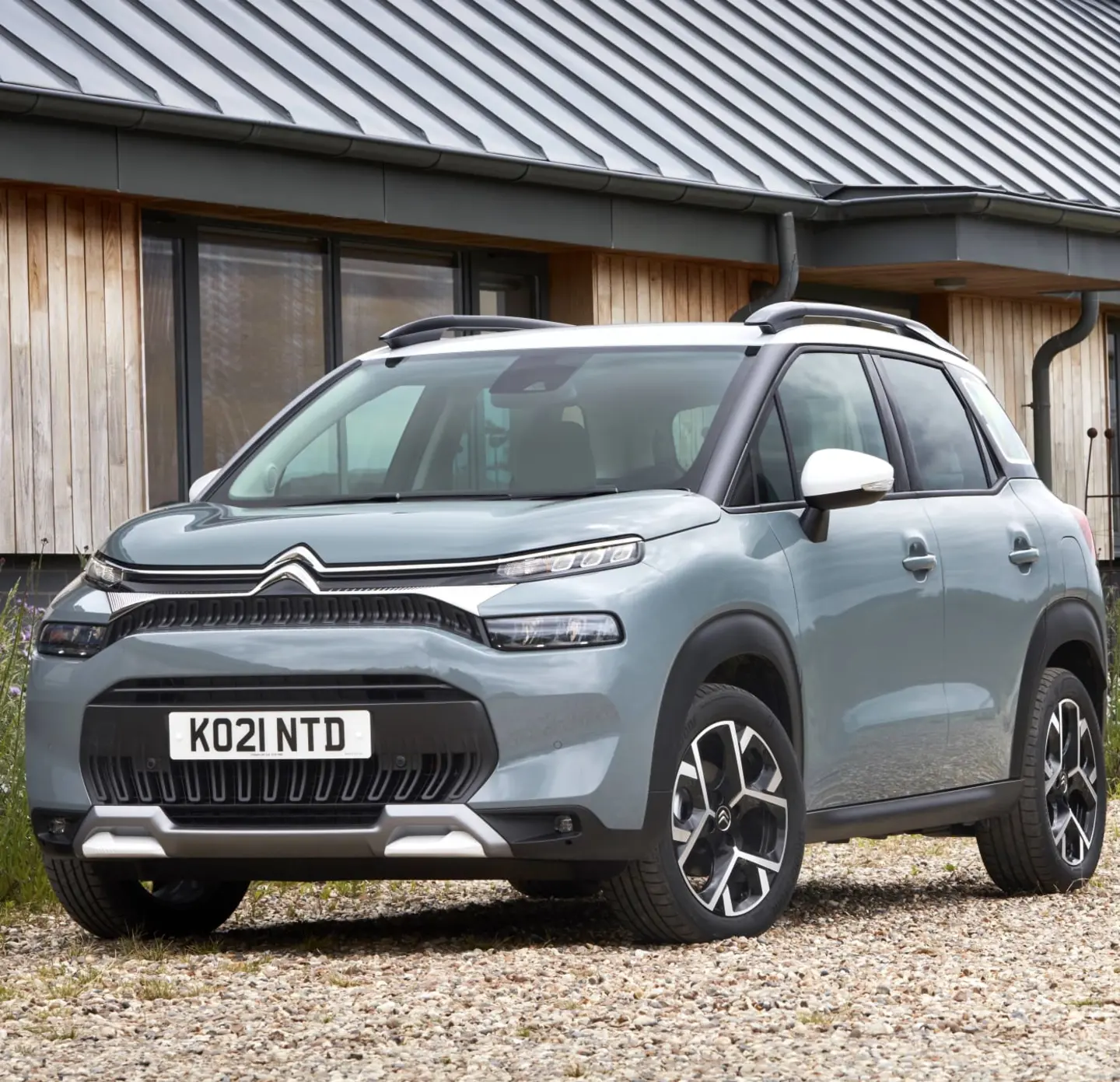 Blue Citroen C3 Aircross parked on gravel outside of a building.