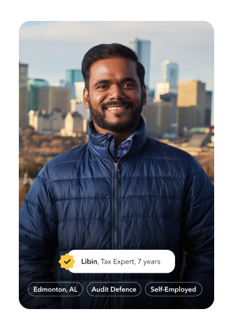Libin, a tax expert of 8 years, is smiling warmly in a park in Edmonton with the city skyline behind him.