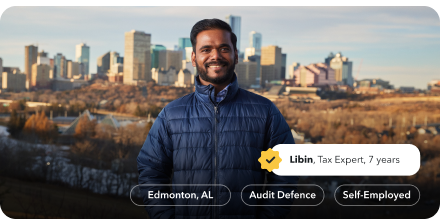 Libin, a tax expert of 8 years, is smiling warmly in a park in Edmonton with the city skyline behind him.