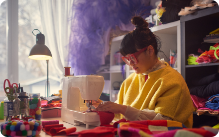 Une styliste élégante travaille avec des tissus sur une machine à coudre dans son studio.