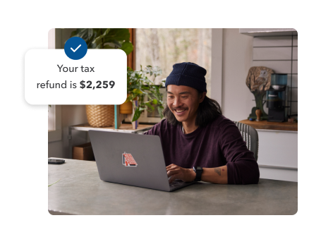 A young man smiling while working on his laptop in his home setting. Secondary illustration with “Your tax refund is $2,259” text and checkmark.