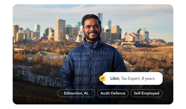 Libin, a tax expert of 8 years, is smiling warmly in a park in Edmonton with the city skyline behind him.