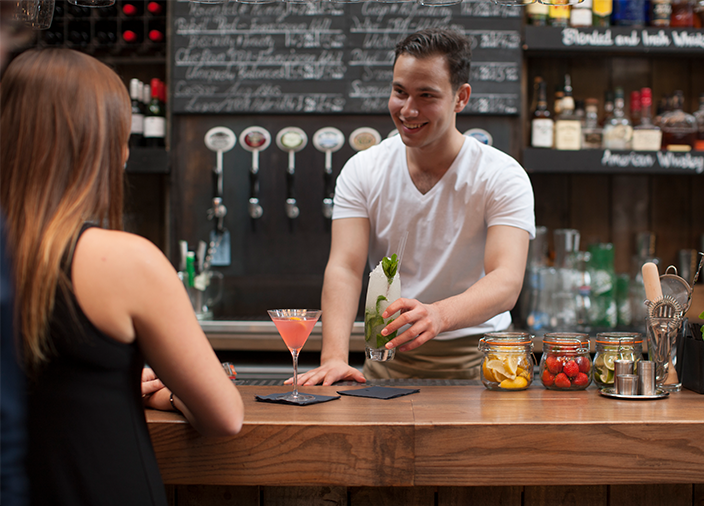 Bartender passing a cocktail to a customer