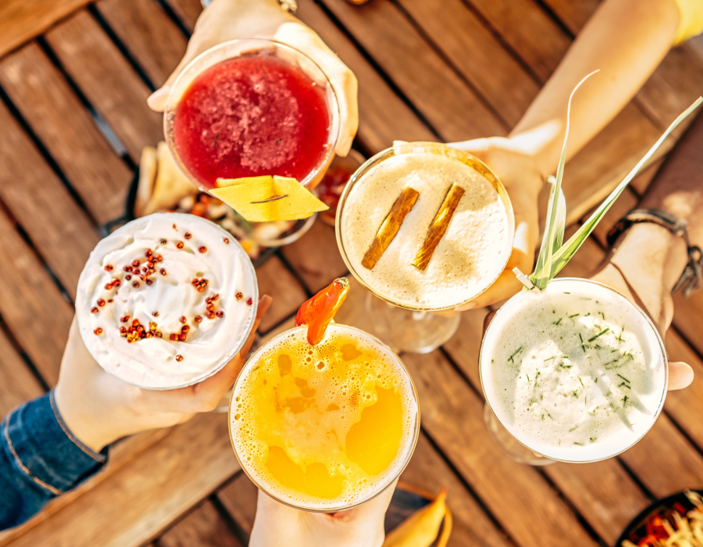 Hands holding together five different types of cocktails. 