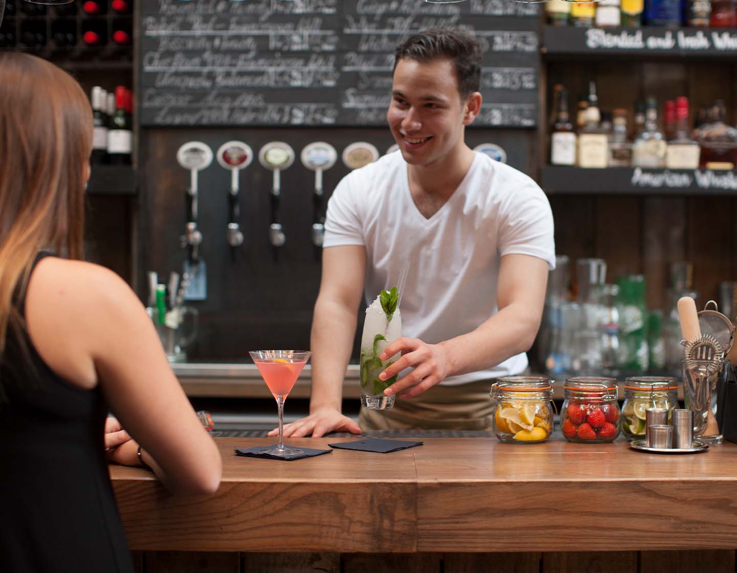 Bartender servindo coquetel para cliente no bar