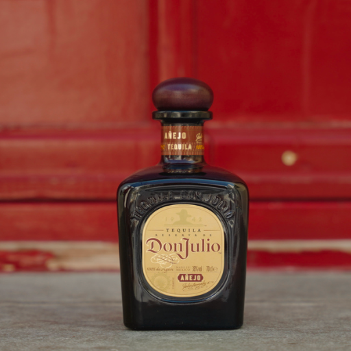 Bottle of Don Julio Añejo tequila standing in front of red door