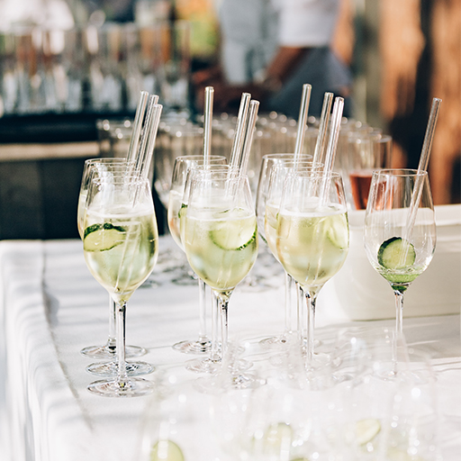 A group of identical apéritif glasses with glass straws and ice with a slice of cucumber. 