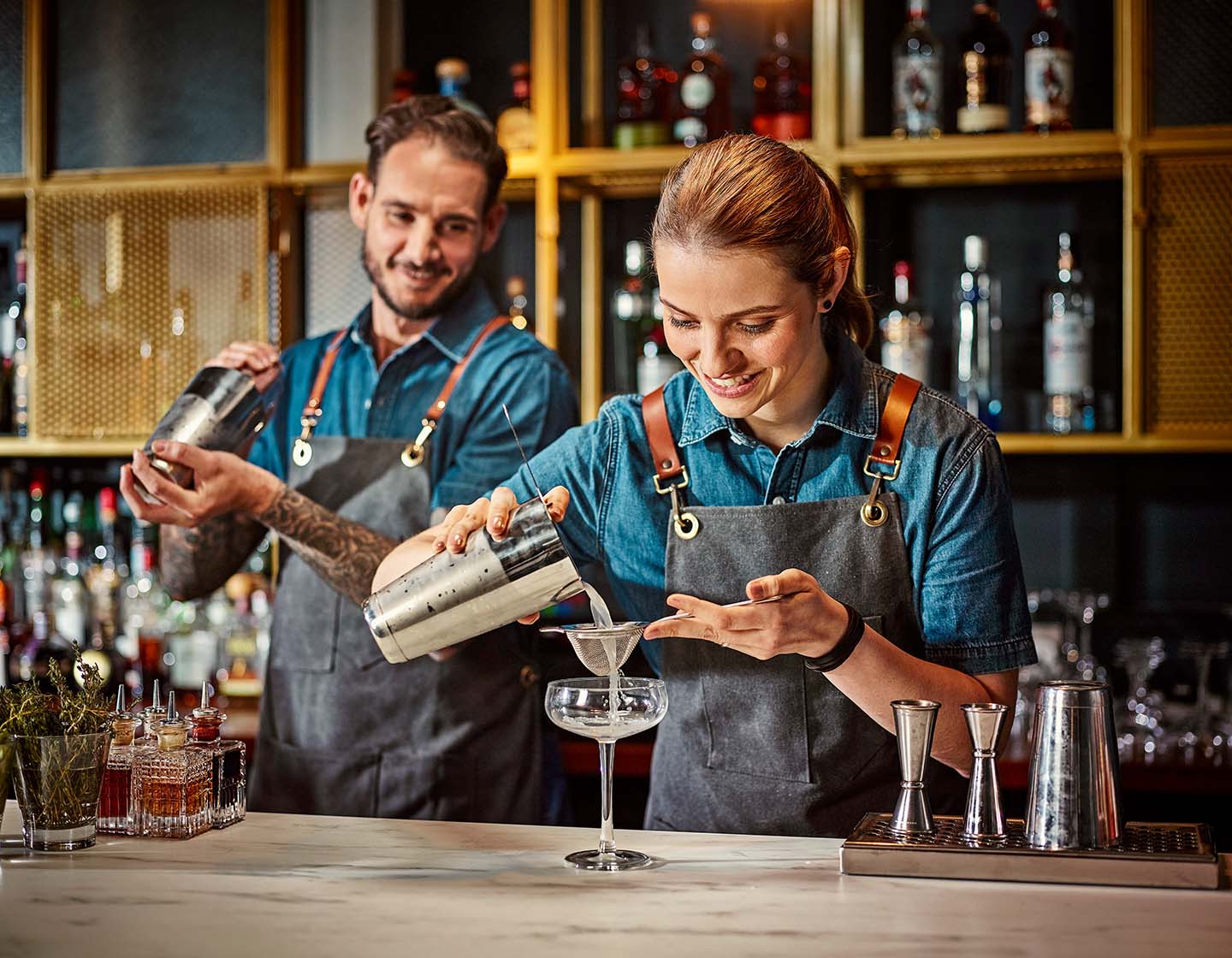 Zwei Barkeeper arbeiten hinter der Bar und schütteln gemeinsam Cocktails