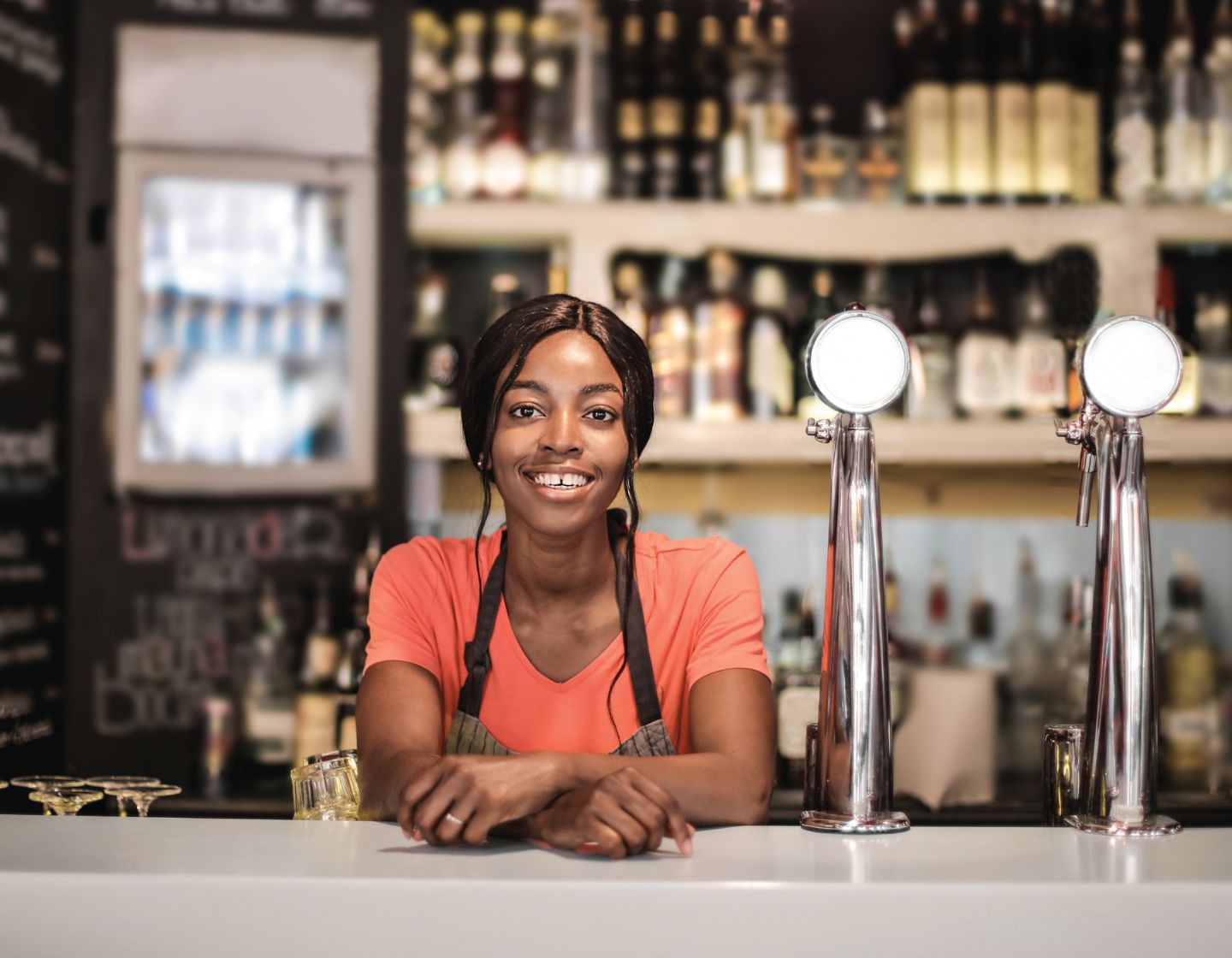 Smiling bartender leaning on a bar.