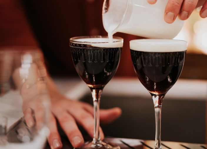 Two irish coffee cocktails being prepared.