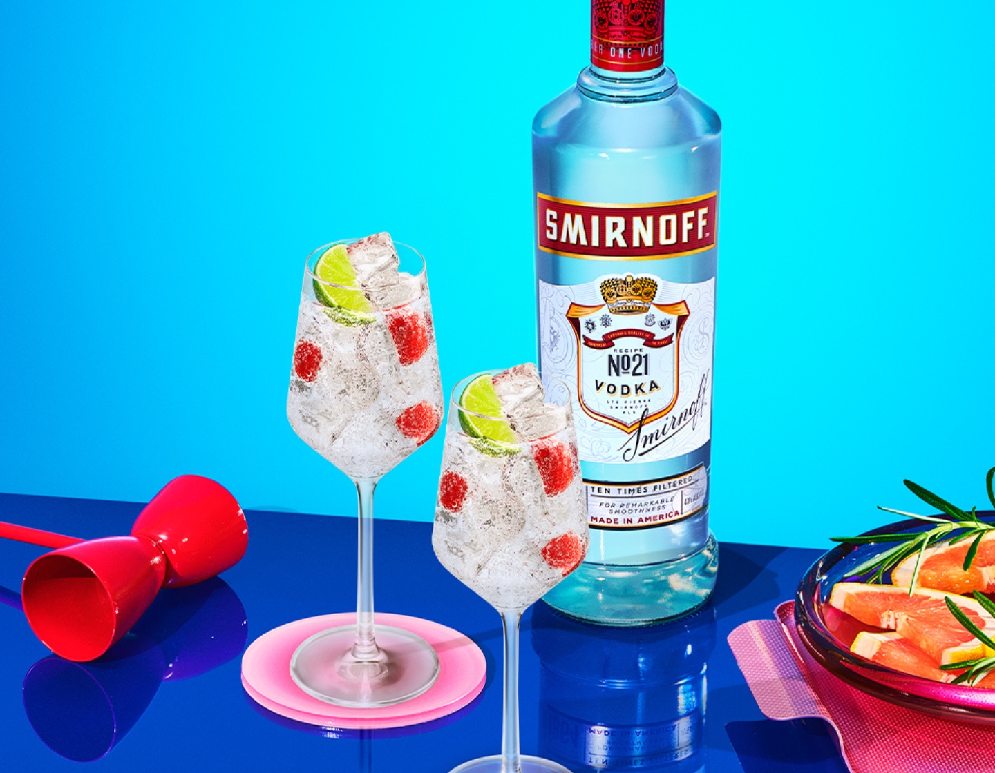 Smirnoff No 21 vodka bottle with two iced glasses on a blue background