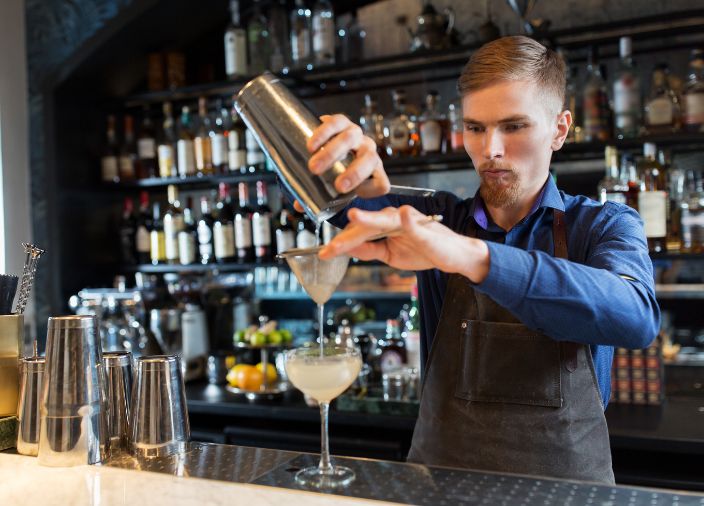 Bartender straining a drink into a cocktail glass
