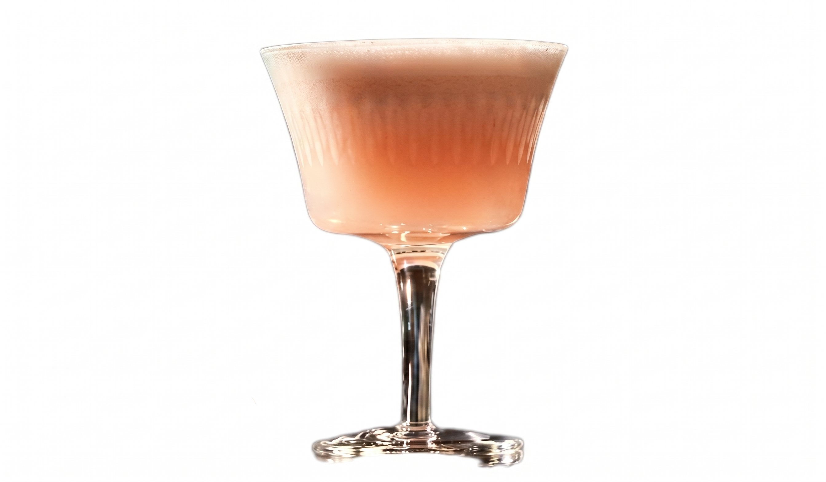 Taça de haste elegante com leves ranhuras verticais contendo um coquetel opaco em tom rosa-pêssego. A bebida é finalizada com uma espessa e suave camada de espuma clara no topo. Fundo branco isolado.