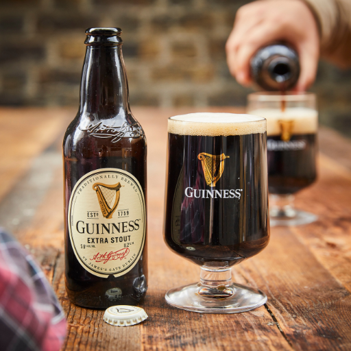 Botellín de Guinness Extra Sout sobre una mesa junto a una pinta llena de Guinness