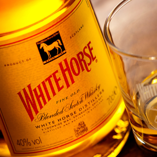 Garrafa de whisky White Horse na mesa ao lado de um copo de whisky puro 