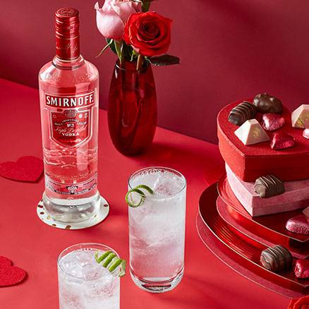 Bottle of Smirnoff vodka, 2 cocktails in rock glasses on a Valentine’s Day themed table