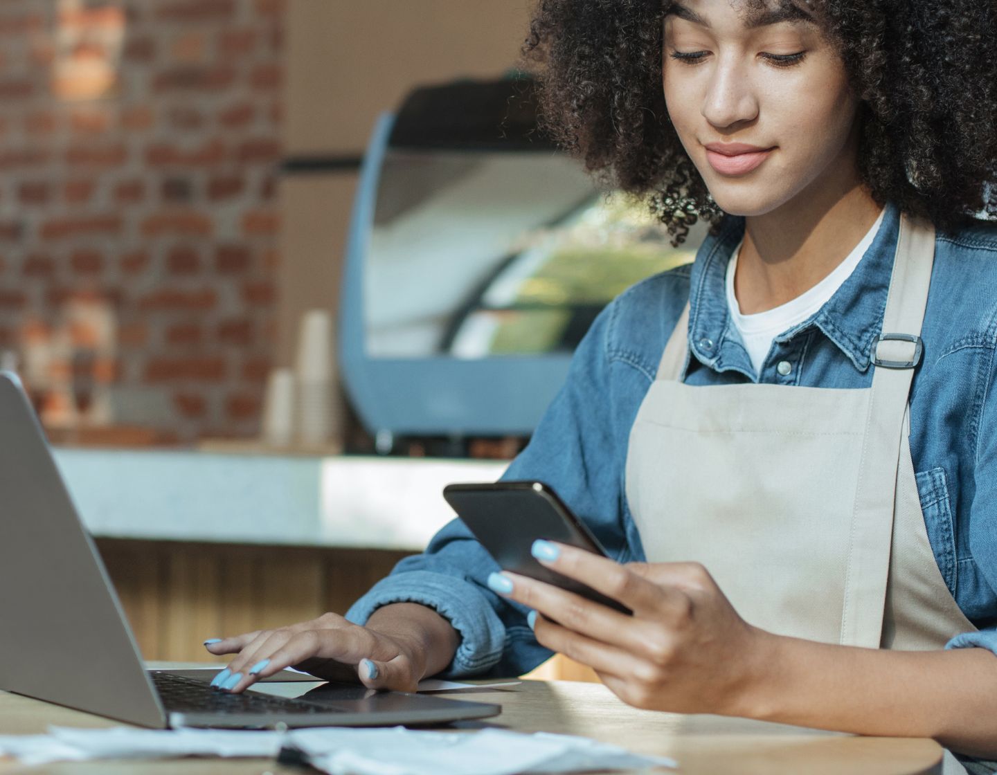 Woman looking at mobile phone and laptop