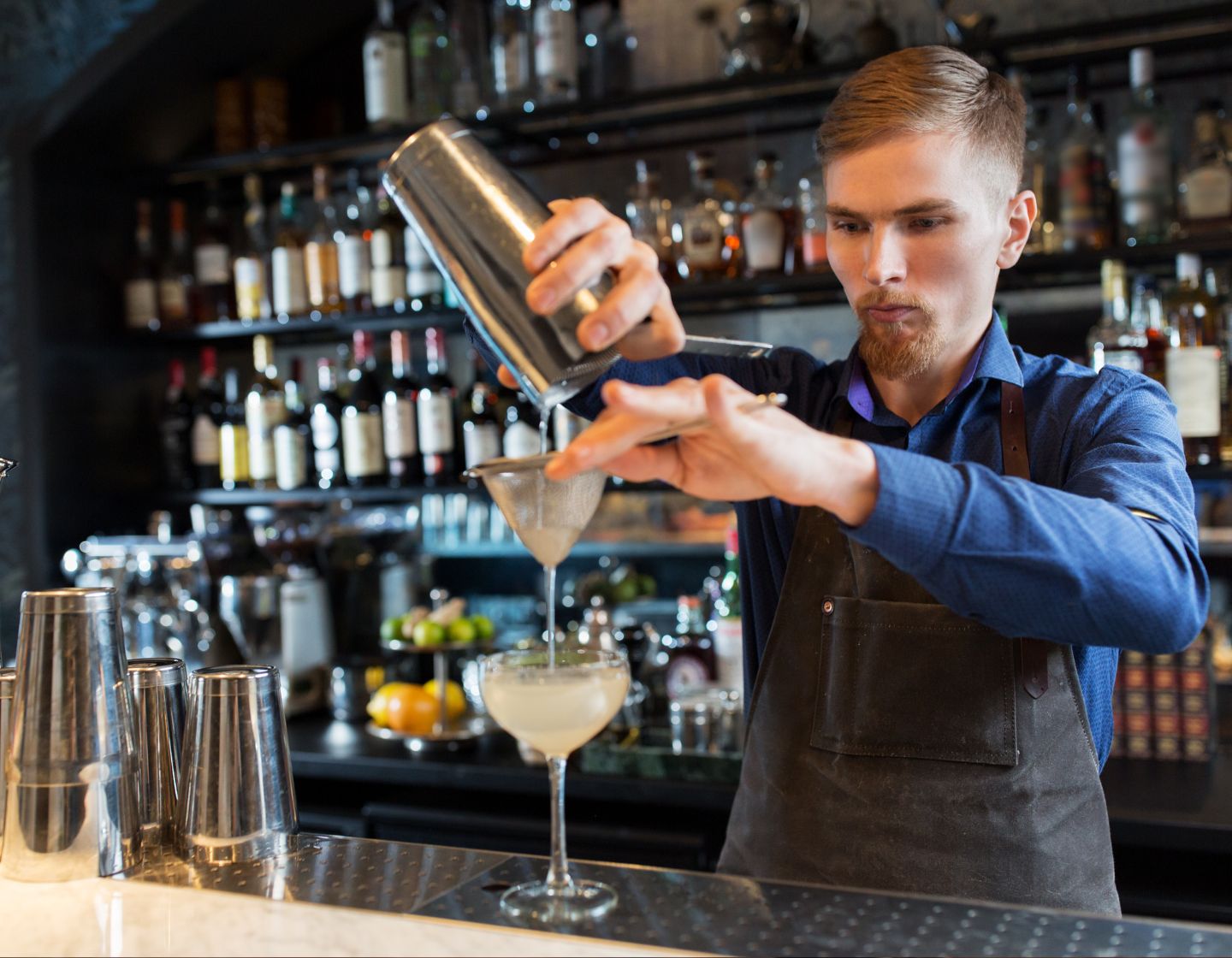 bartender en barra colando un coctel