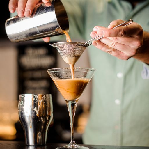 Coquetel de café sendo servido em um copo por um barman.