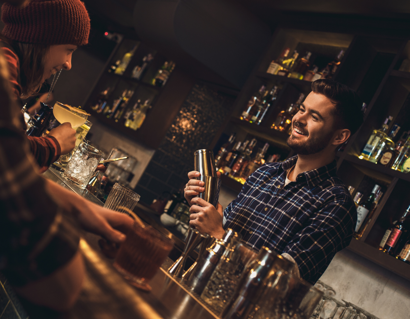 Homem servindo um coquetel a uma mulher com um sorriso atrás de um bar