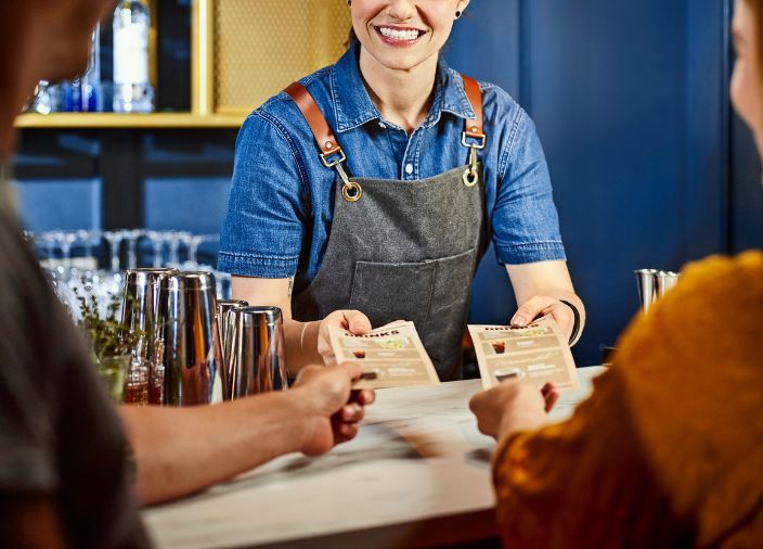 Bartender behind bar giving customers a drinks menu