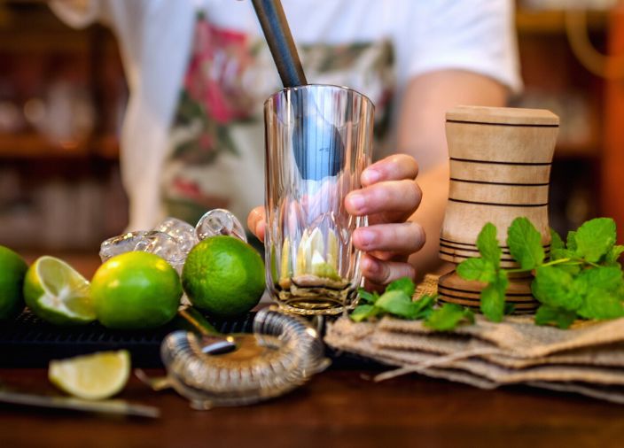 Muddling limes and mint leaves for a cocktail.