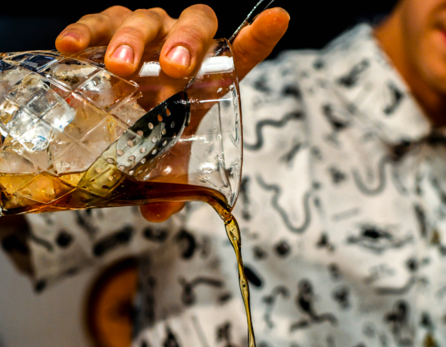 Bartender pouring a spirit from a crystal glass. 