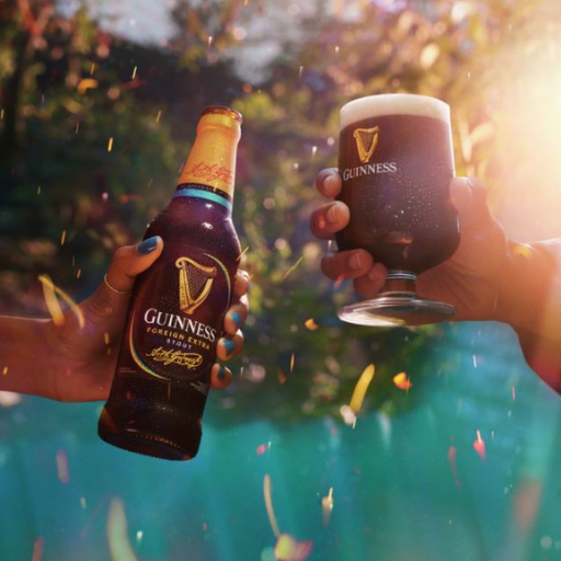 Botella de Guinness Foreign Extra Stout brindando con un vaso de Guinness 