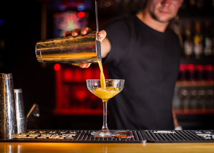 Bartender pouring cocktail using from shaker.