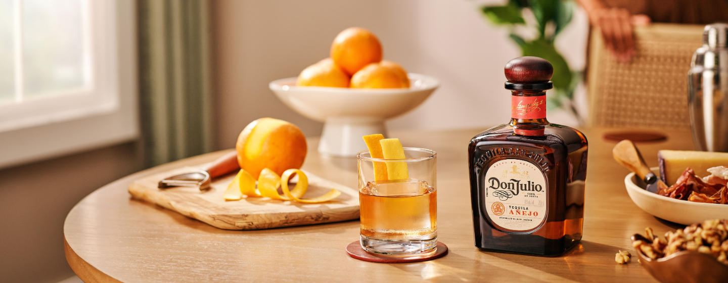 Bottle of Don Julio Añejo tequila and oranges standing in front of red door