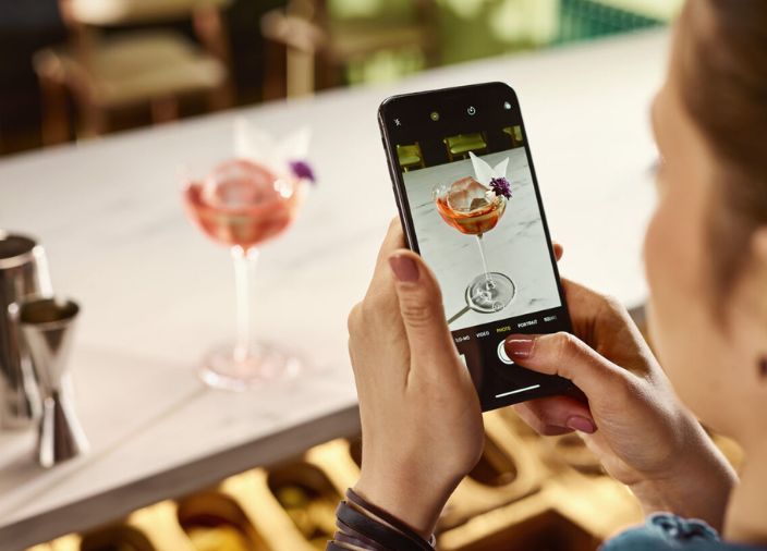 woman taking a picture of a cocktail with her phone