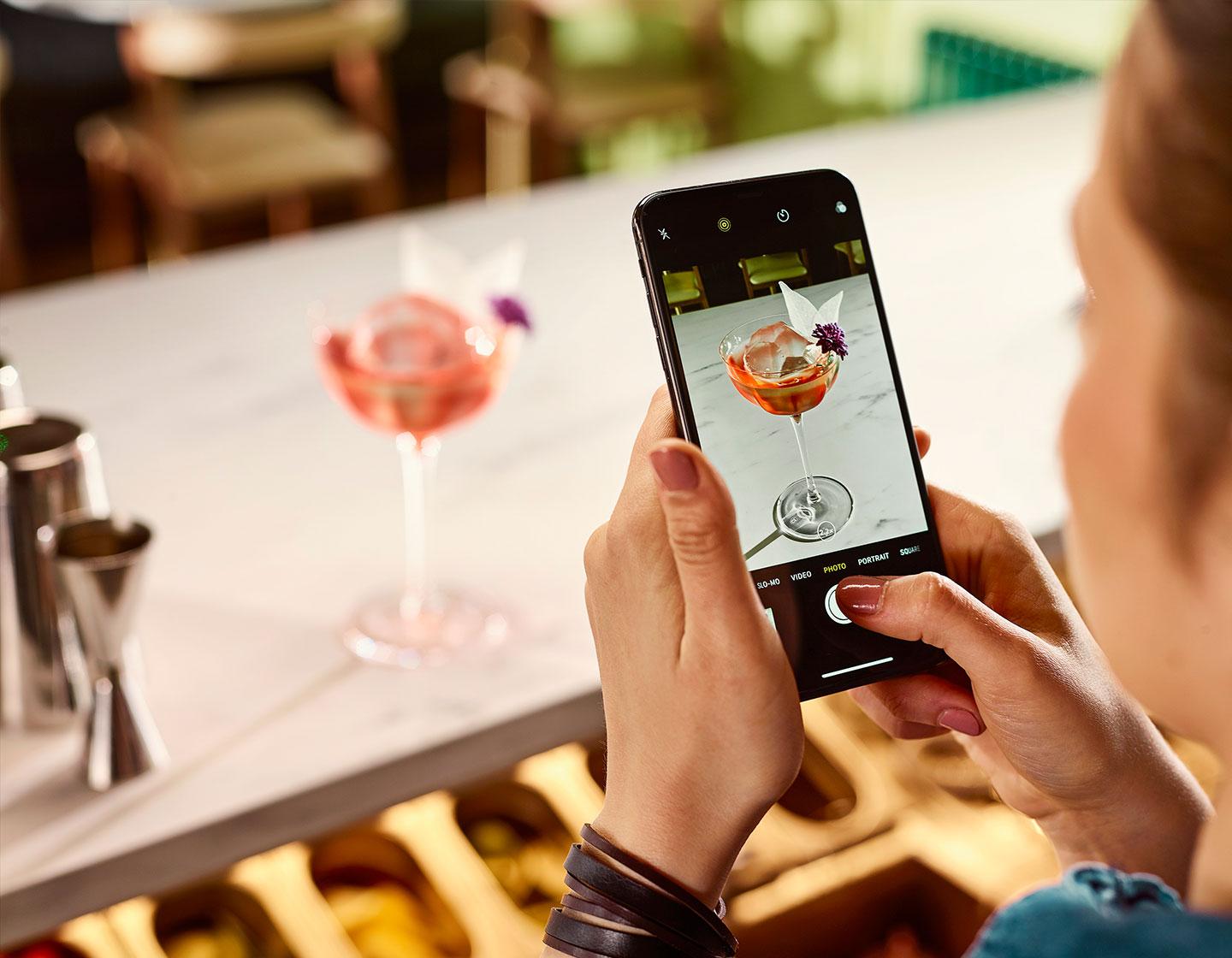 Bar staff taking photo of cocktail on mobile phone